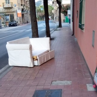 Divano abbandonato in mezzo al marciapiede in pieno centro: l'immagine tra stupore e indignazione