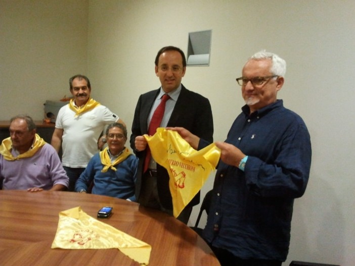 Nella foto il presidente dei “Fieui di caruggi” mentre consegna il foulard firmato da Roberto Vecchioni all’assessore regionale al Turismo Berlangieri
