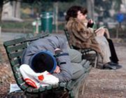 Un clochard si ripara dal freddo con una coperta Un clochard si ripara dal freddo con una coperta