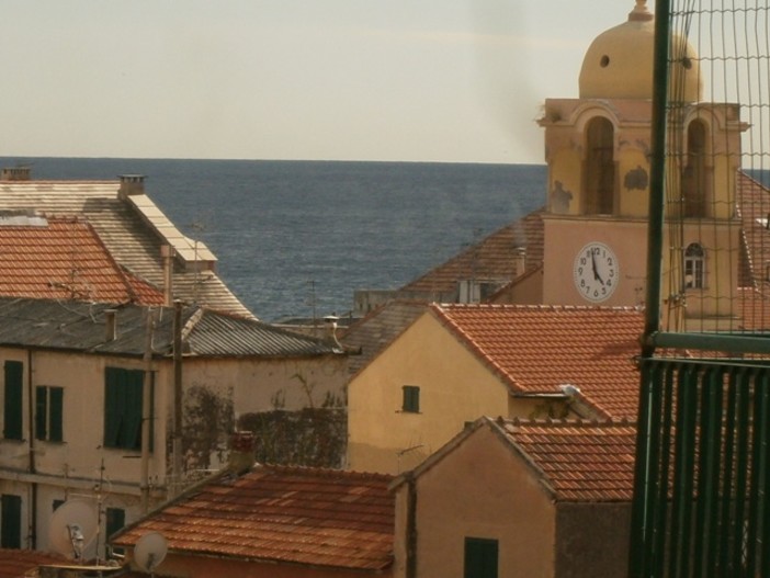 Il camino e il fumo che si innalza sui tetti di Finale Ligure