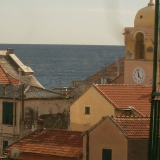 Il camino e il fumo che si innalza sui tetti di Finale Ligure