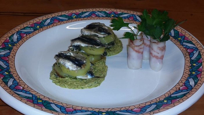 Infornata di sardelle e patate profumate con aglio prezzemolo e vino bianco su salsa verde;